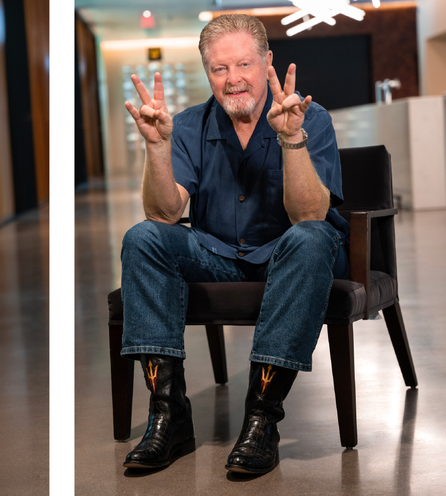 Bill Kent in blue button up sitting in a chair with hands and fingers up except his ring fingers