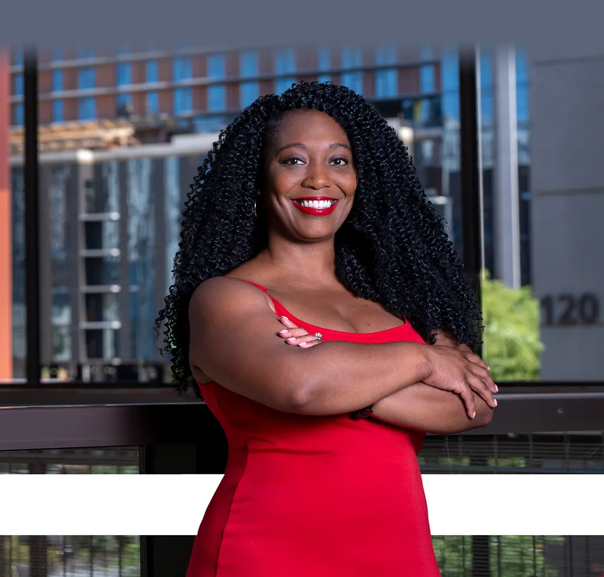 Whitney Harvey wearing a red dress and crossing her arms while smiling