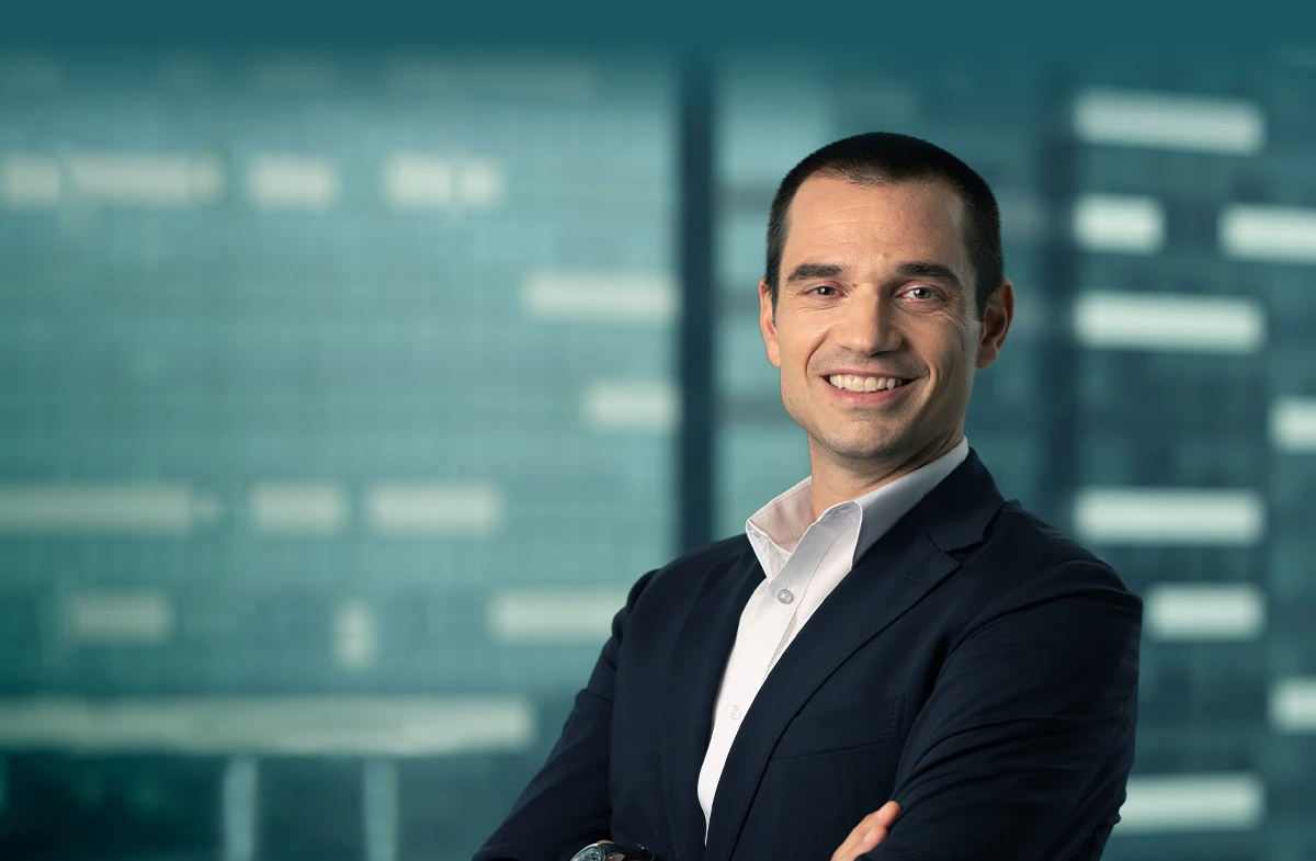 Jerome Bigio wearing a white button up shirt and black blazer with his arms crossed and smiling at the camera