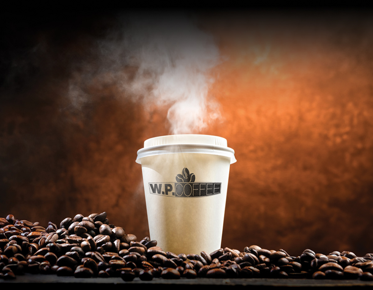 hot coffee in a paper cup with W.P. Coffee logo sitting in pile of coffee beans 