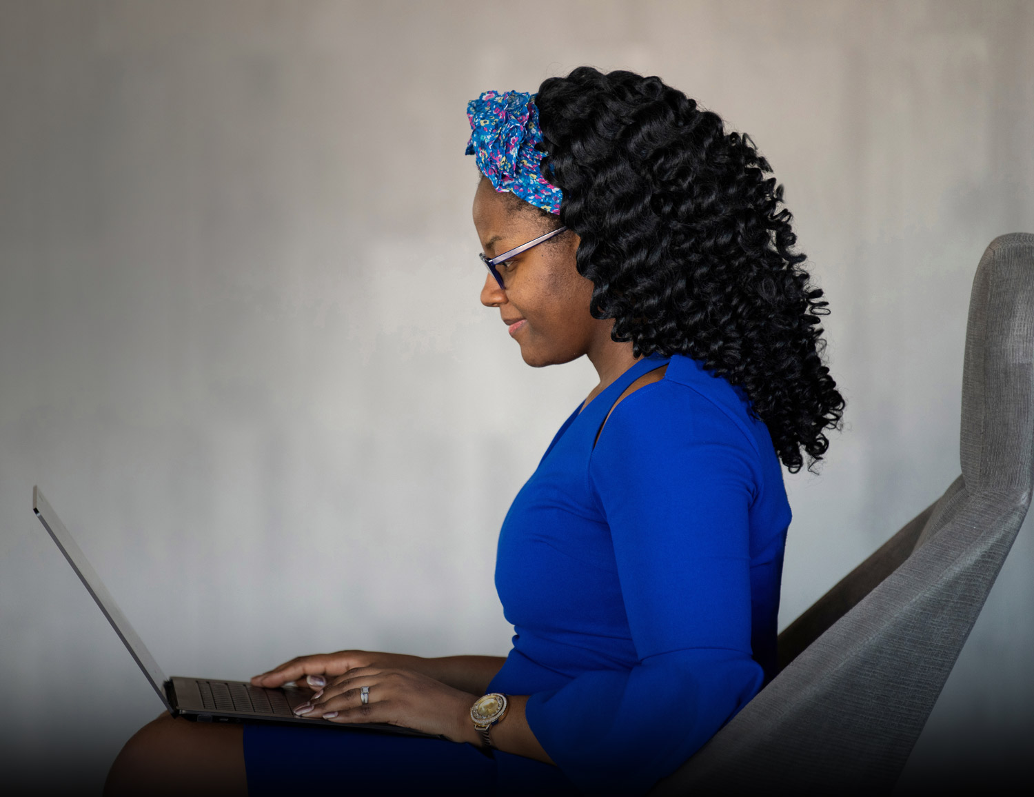 woman in business attire seated while typing on a laptop