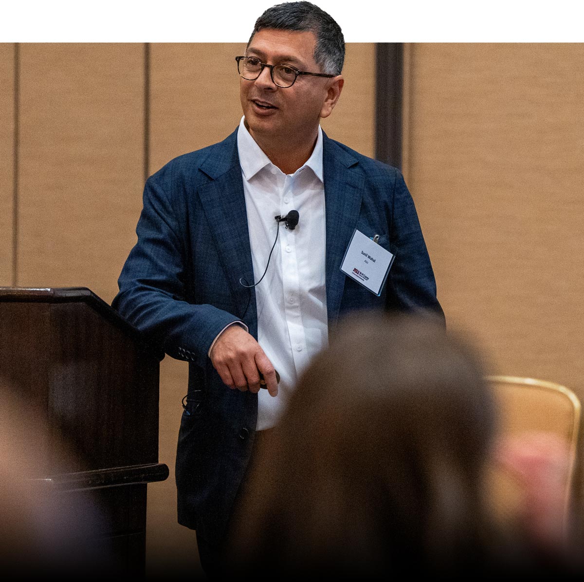 professor sunil wahal leaning against podium while speaking to his audience 