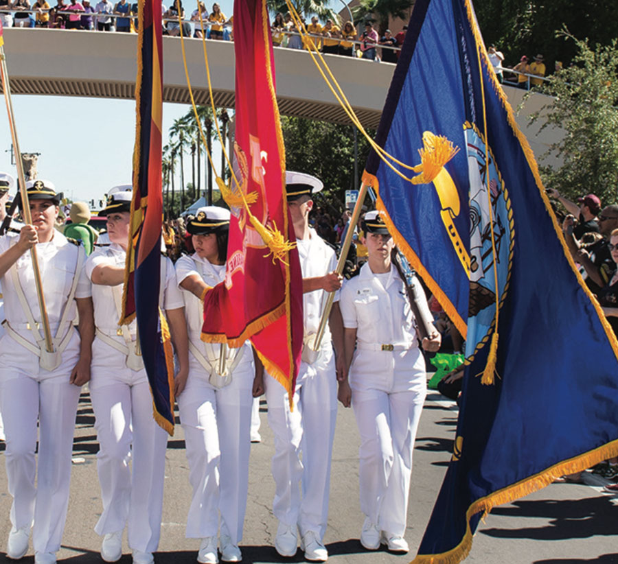 cropped view of NROTC members presenting flags at a large event