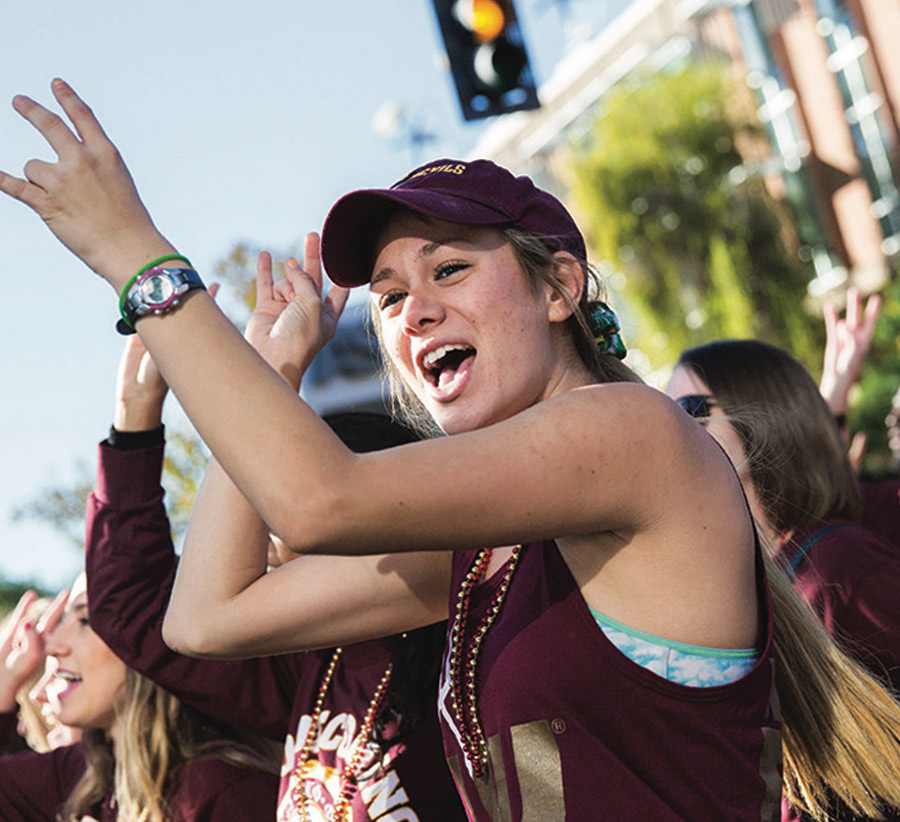 a female ASU student cheers with her hands in the air while attending a rally