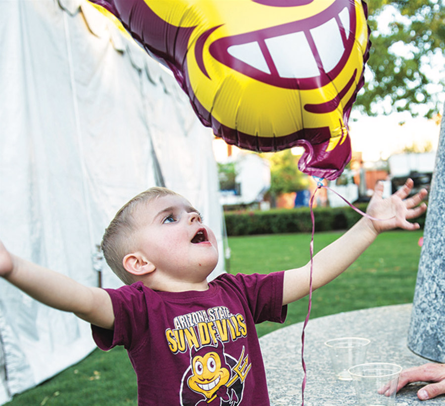 a little boy plays with a Sparky the Sun Devil balloon while wearing an Arizona State Sun Devils t-shirt