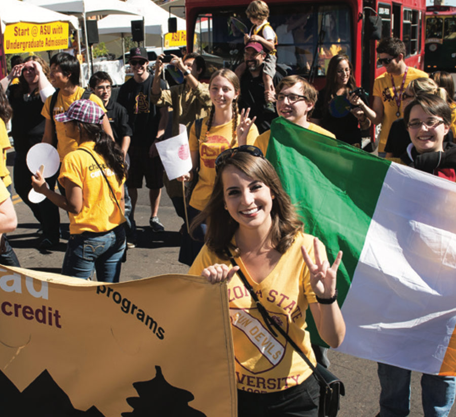 action shot of attendees holding signs and waving while walking in an event procession