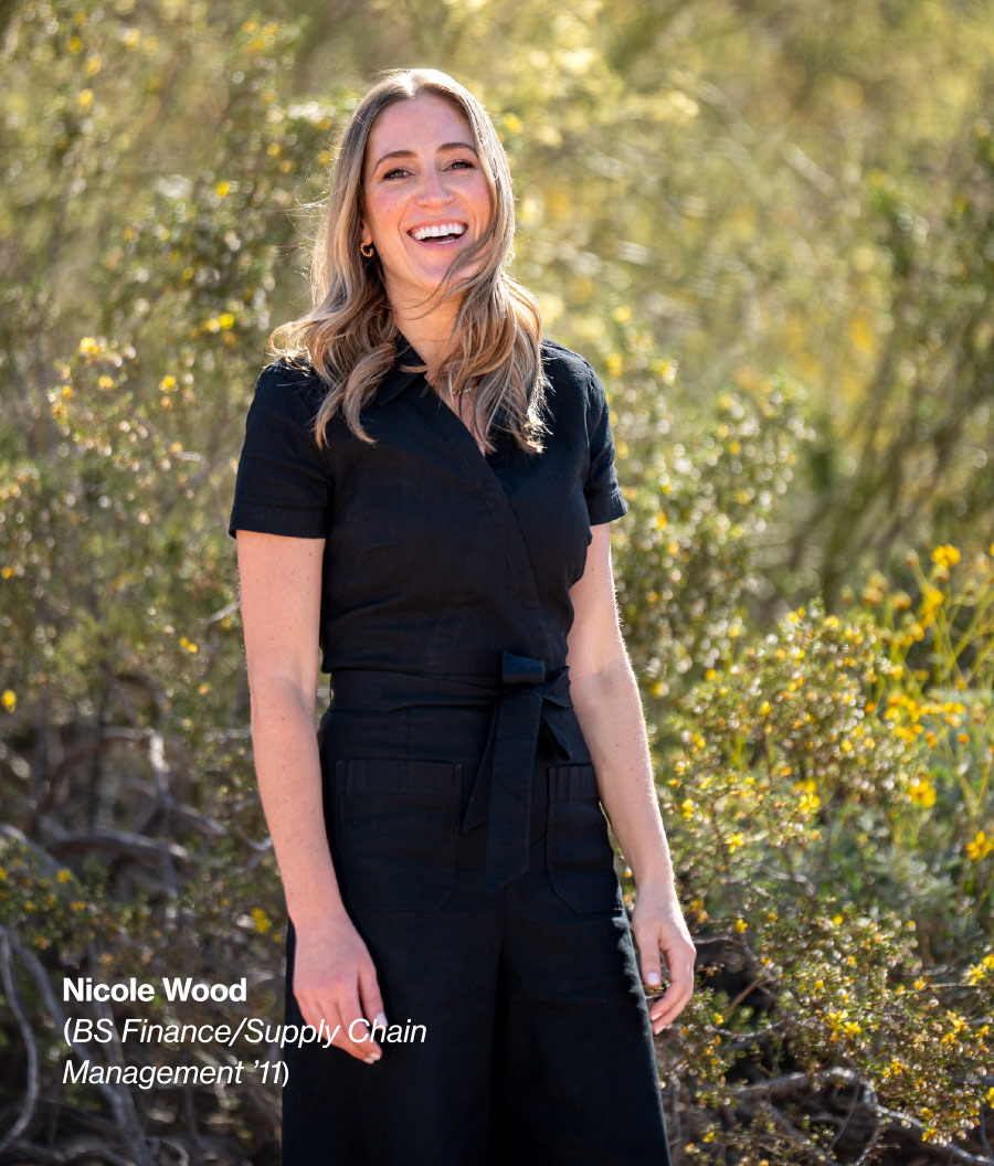 Nicole Wood smiling in grass field with bushes behind her