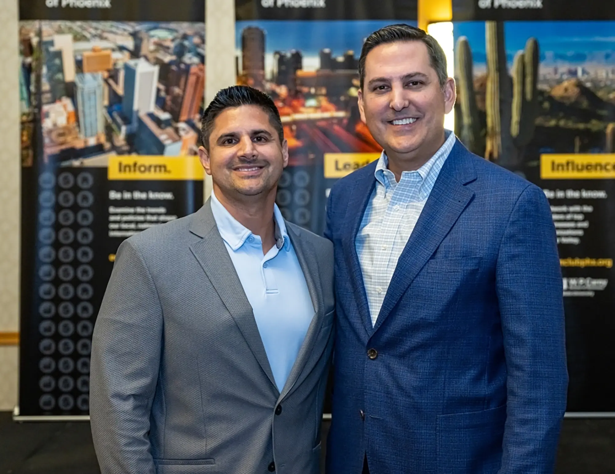 Knight-Swift Transportation CEO Adam Miller (BS Accountancy ’02) is on the left of former CEO David Jackson (BS Global Business/Financial Management ’00) at the Economic Club of Phoenix event celebrating Jackson’s recognition as the 2024 Executive of the Year as both men are smiling together standing right beside each other for a photograph in their own respective professional business attire