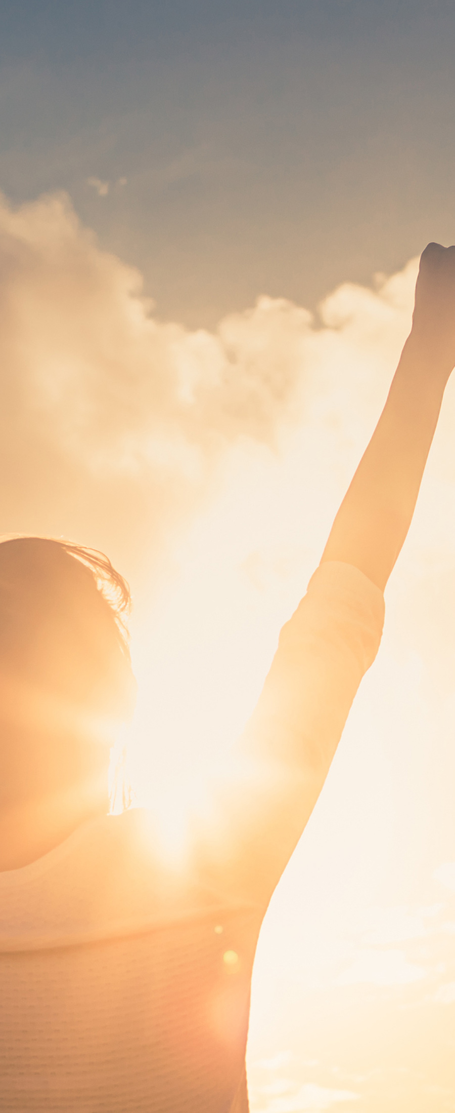 person with hands in the air with sun peeking through