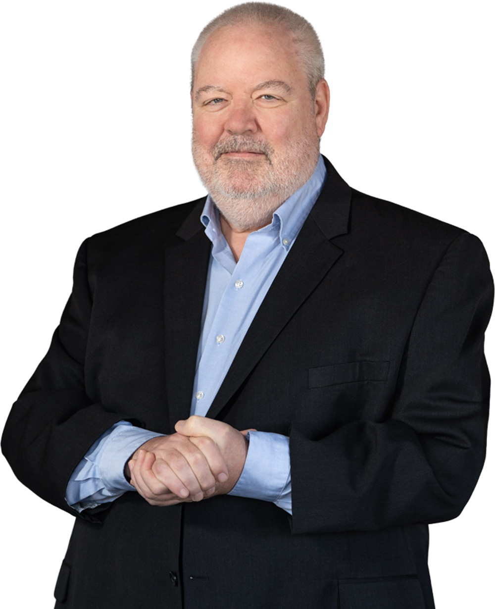 Man in a dark suit and light blue shirt with clasped hands.