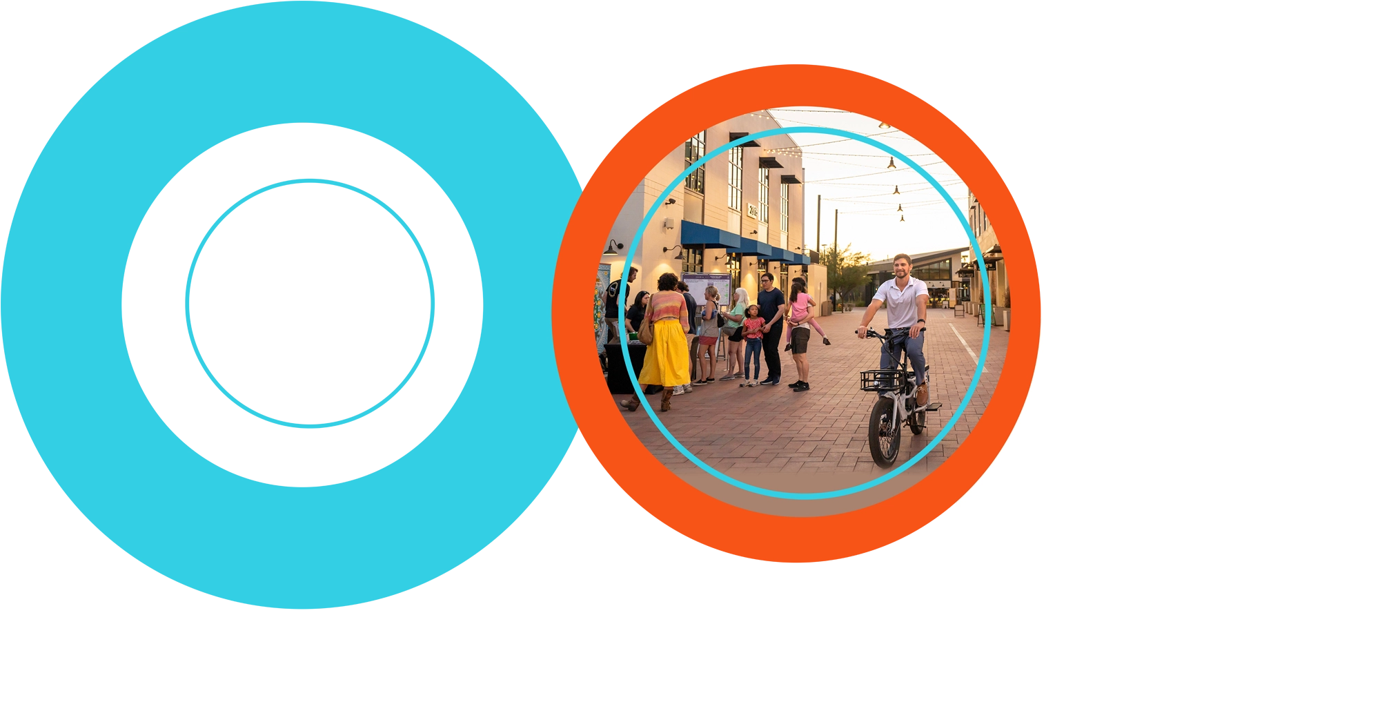 Rob Maloney is shown smiling while riding a white e-bike with a front basket down a brick-paved, pedestrian street. In the background to the left, a small group of people gathers near a table in front of a modern commercial building during the golden hour. The street is lined with businesses and illuminated by overhead string lights.