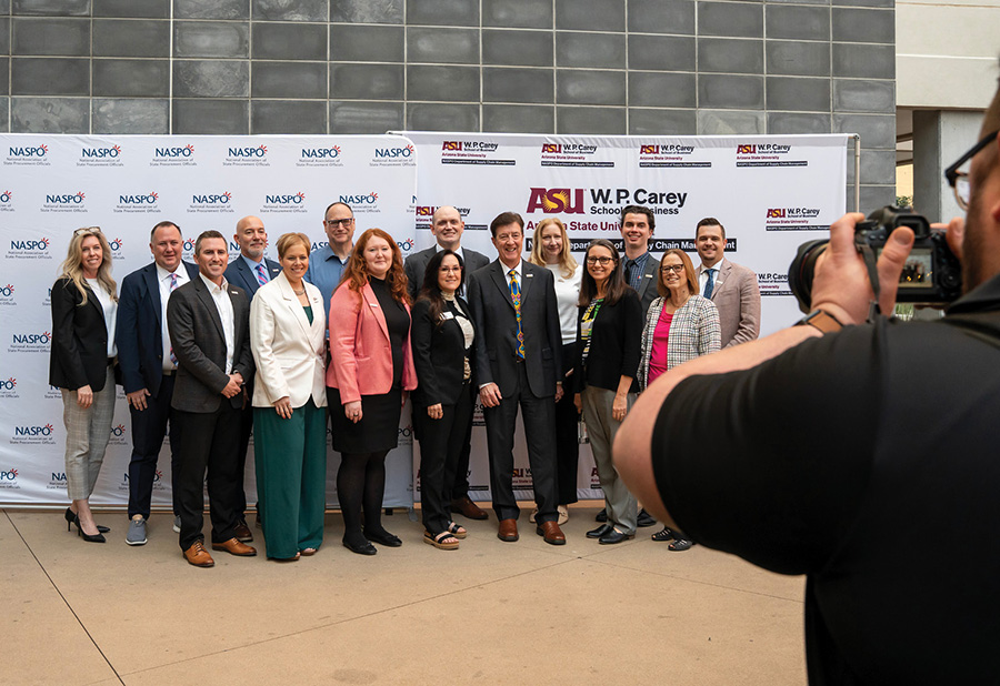 A group of business professionals posing together while a photographer takes their picture.