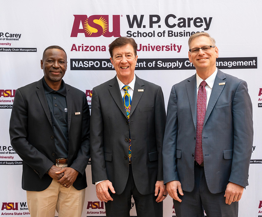 Three professional men smiling together in front of an ASU W. P. Carey backdrop.