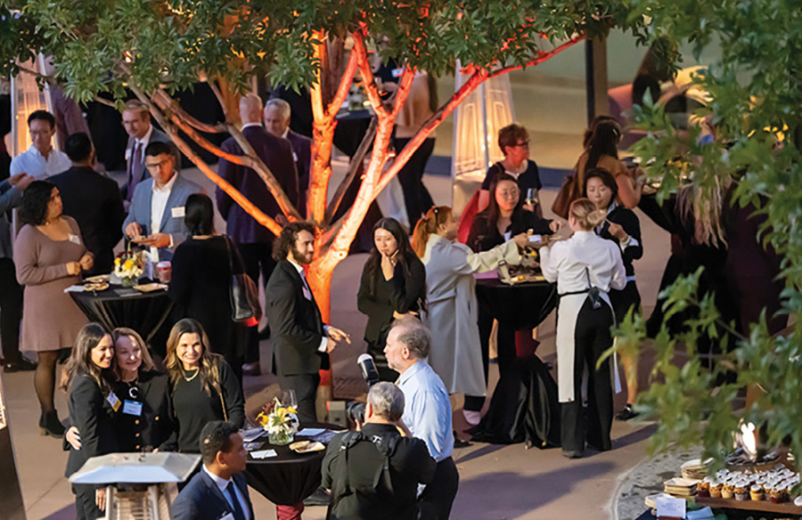 Guests socializing around high-top tables at an outdoor evening reception event.