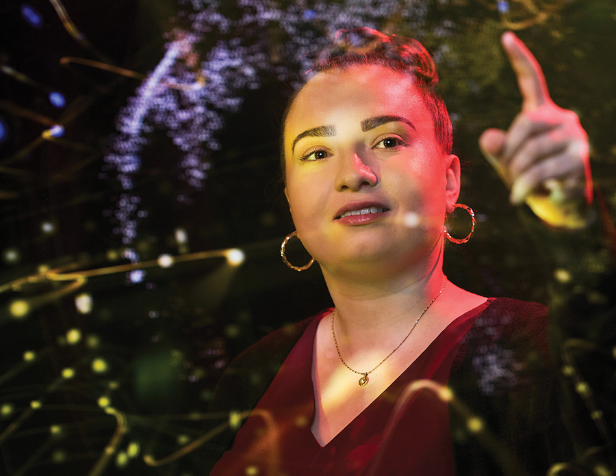 Woman with hair in a bun pointing upward through glowing overlay artwork lines.